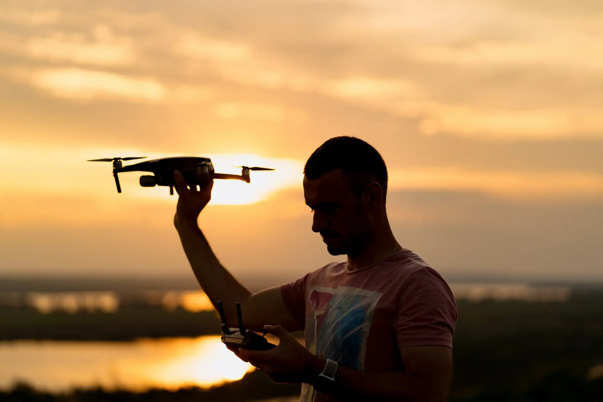 Drone Pilot Holding Drone While Checking Remote A man holding a drone in one hand while focused on the controls in the other, symbolizing expertise and dedication to drone piloting